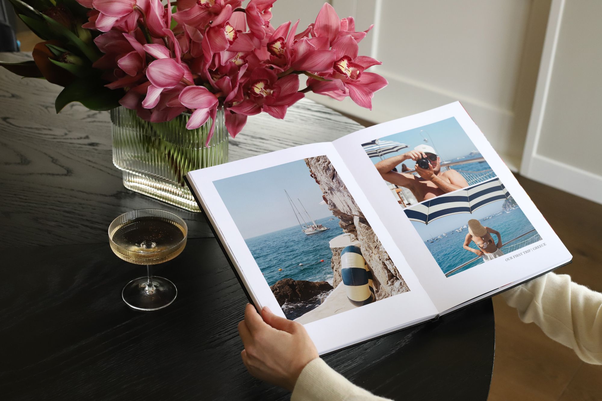 Person holding book on table with travel imagery