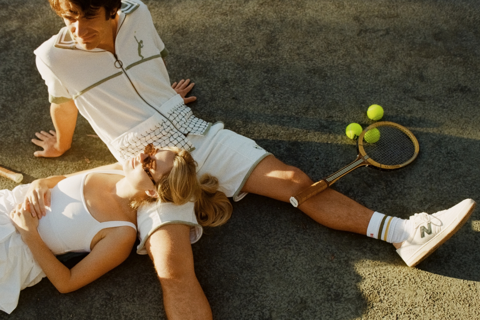 Couple in tennis outfits lying on top of eachother