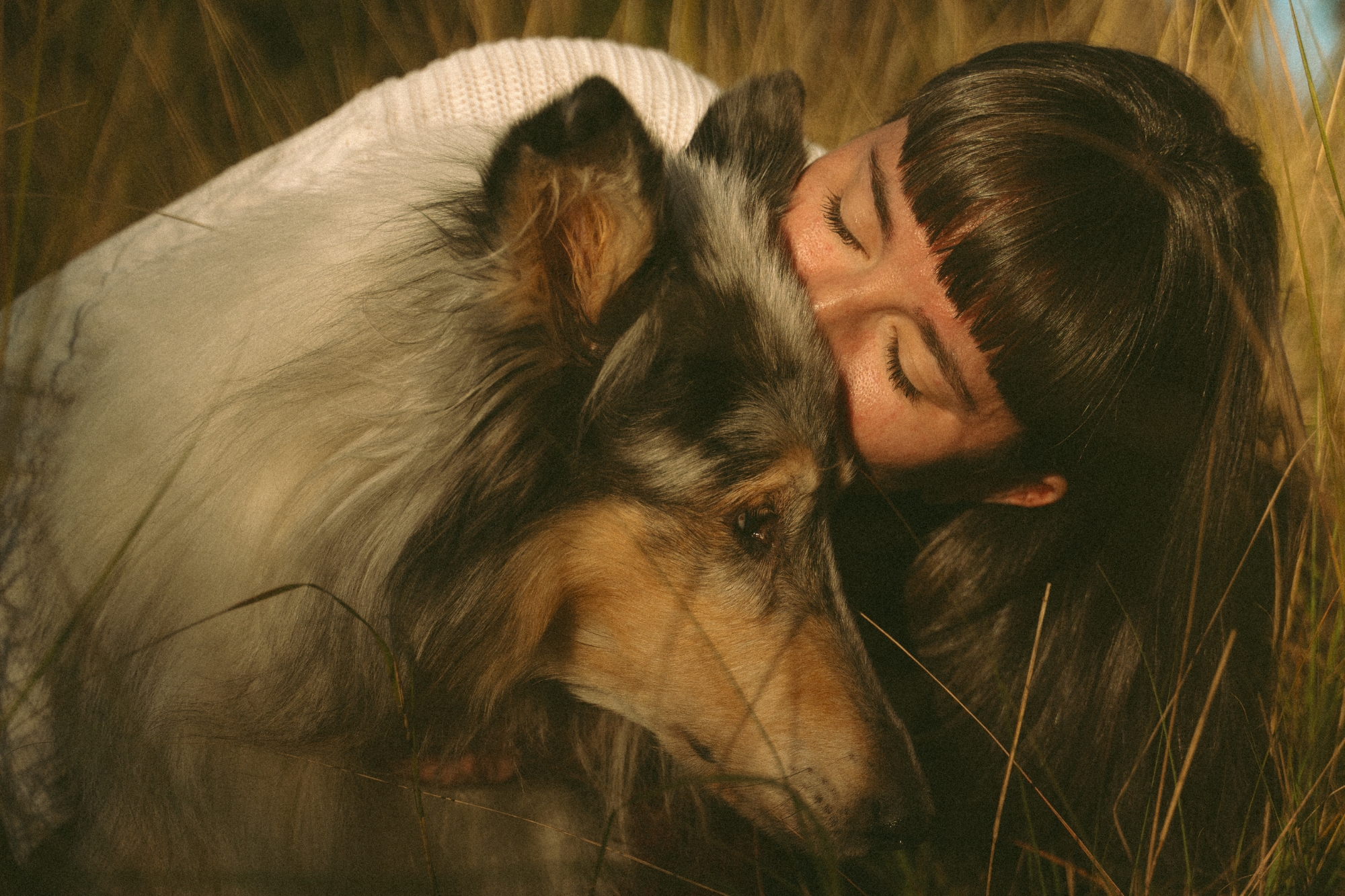 Woman kissing Australian shepherd dog's head.